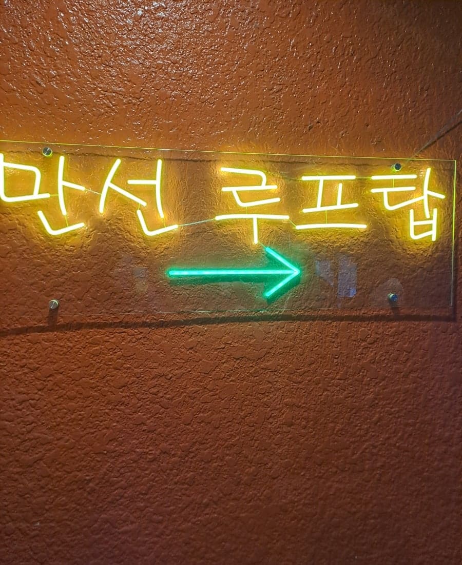 1dusdk는 루프탑으로 향하는 계단 벽의 네온 화살표 사인과, 짐빔 로고 조형물 아래 조명이 가득한 루프탑 풍경을 찍었습니다.