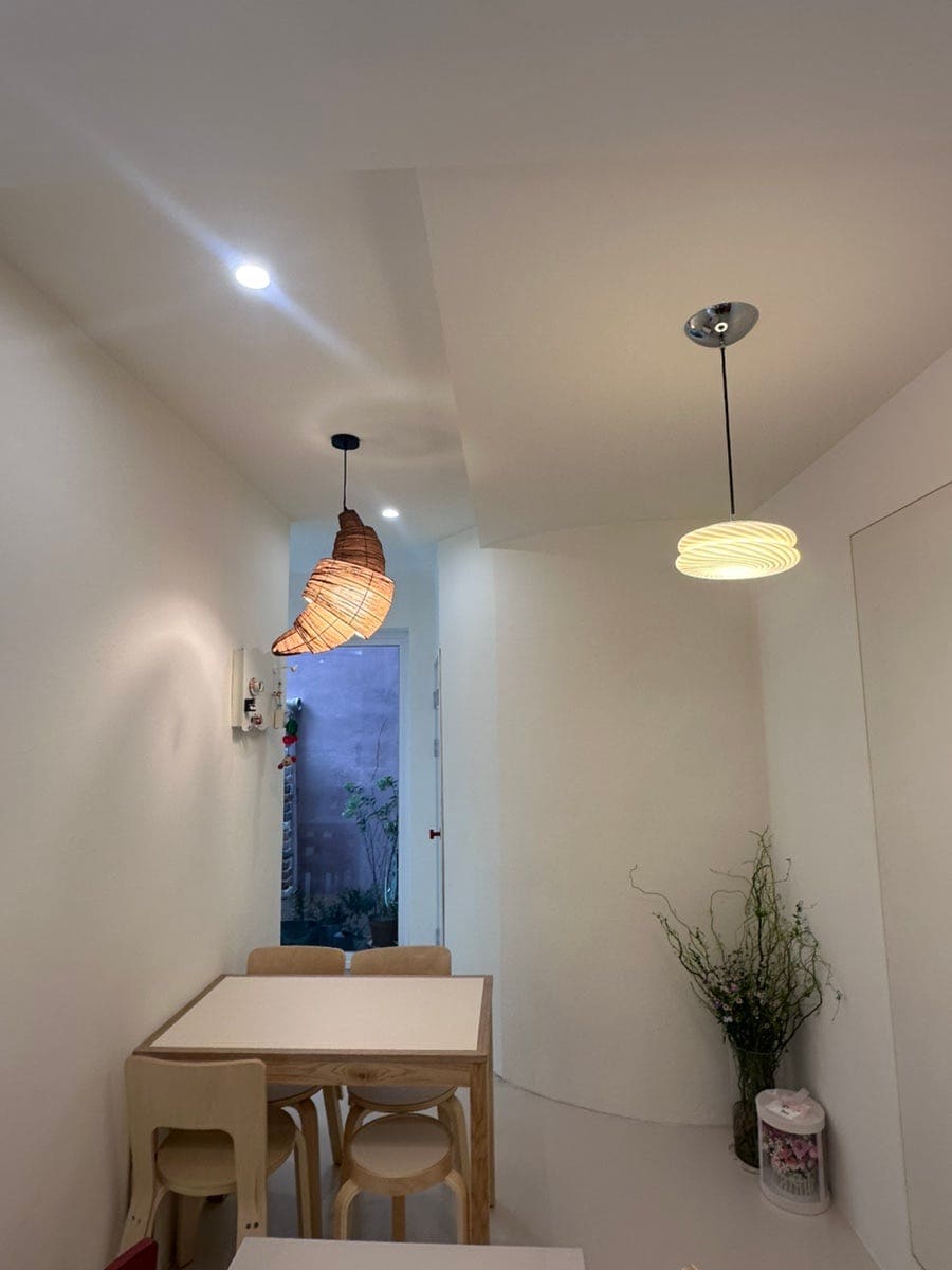 wall1117은 공방 이웃으로 인테리어 공사를 옆에서 지켜봤다며, 아치형 창 너머로 골목이 그대로 보이는 창가 자리와 커다란 크루아상 모양 조명이 걸린 복도를 나란히 남겼습니다.