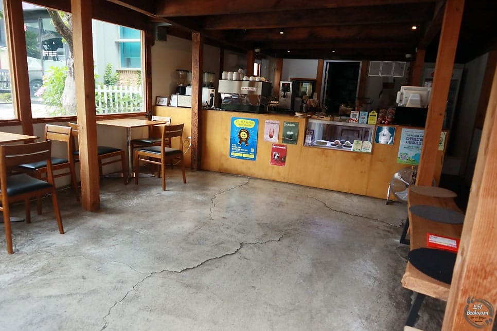 명주동 골목을 산책하다 들렀다는 손님의 사진입니다. 짙은 나무 기둥과 시멘트 바닥이 드러난 1층 자리와, 흰 벽에 걸린 소나무 모양 로고 간판을 함께 담았습니다.