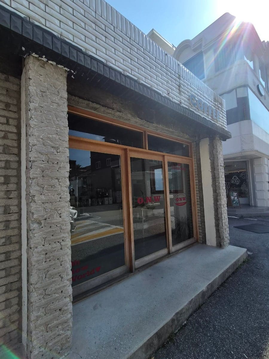 골목을 산책하다 들른 손님이 남긴 사진입니다. 콘크리트를 그대로 살린 벽돌 외관과, 건물 뒤편으로 이어지는 자갈길 주차 공간을 함께 담았습니다.