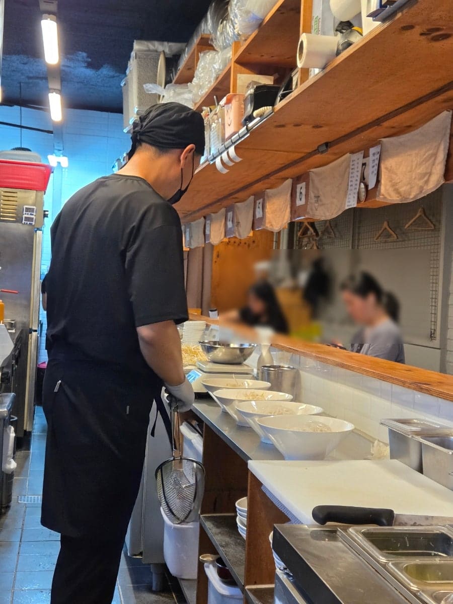 손님들을 향해 국물과 재료를 담은 그릇들이 한 줄로 준비되어 있습니다. 직접 주문을 받고 만드는 과정이 이렇게 투명하면, 위생은 저절로 신뢰가 됩니다.