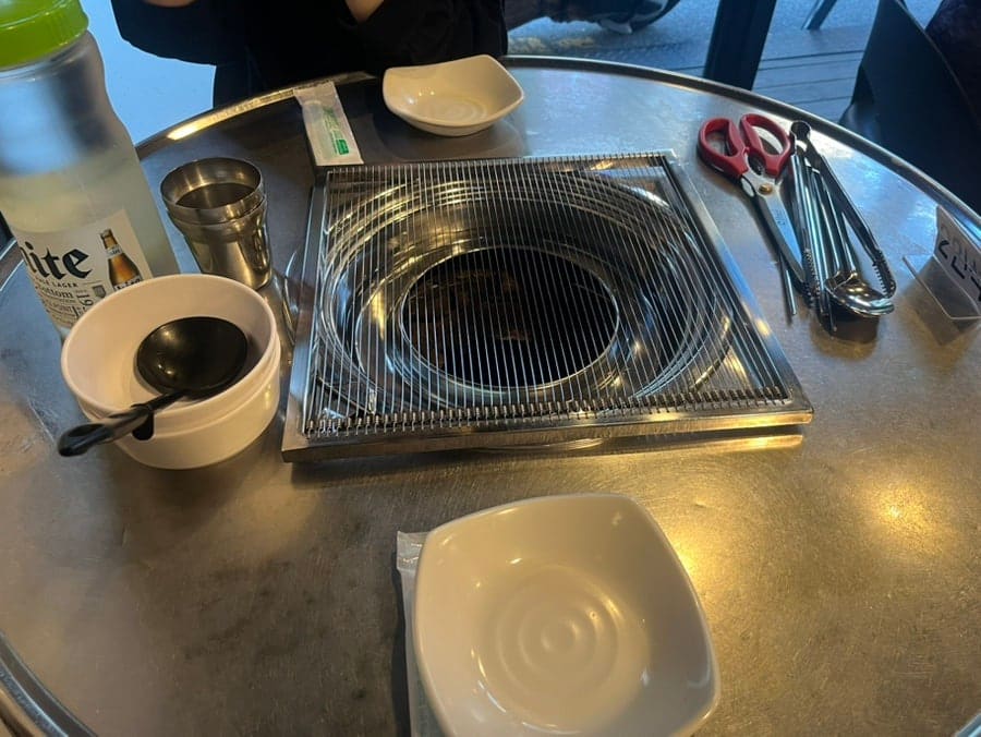 매장 테이블에 준비된 셋업입니다. 금속 숯불 화로와 함께 기본 찬들이 정렬되어 있습니다. 깔끔한 분위기 속에서 식사를 준비할 수 있습니다.