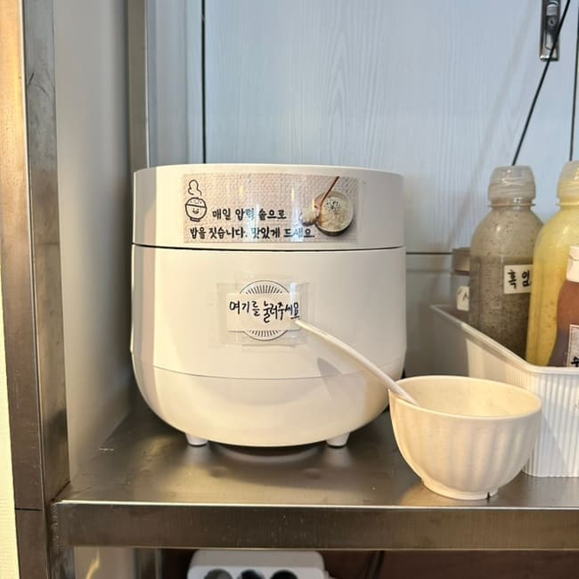 쿠쿠 밥솥이 설치되어 있습니다. 따뜻한 밥이 항상 준비되어 있어 고객들이 필요한 만큼 담을 수 있습니다.