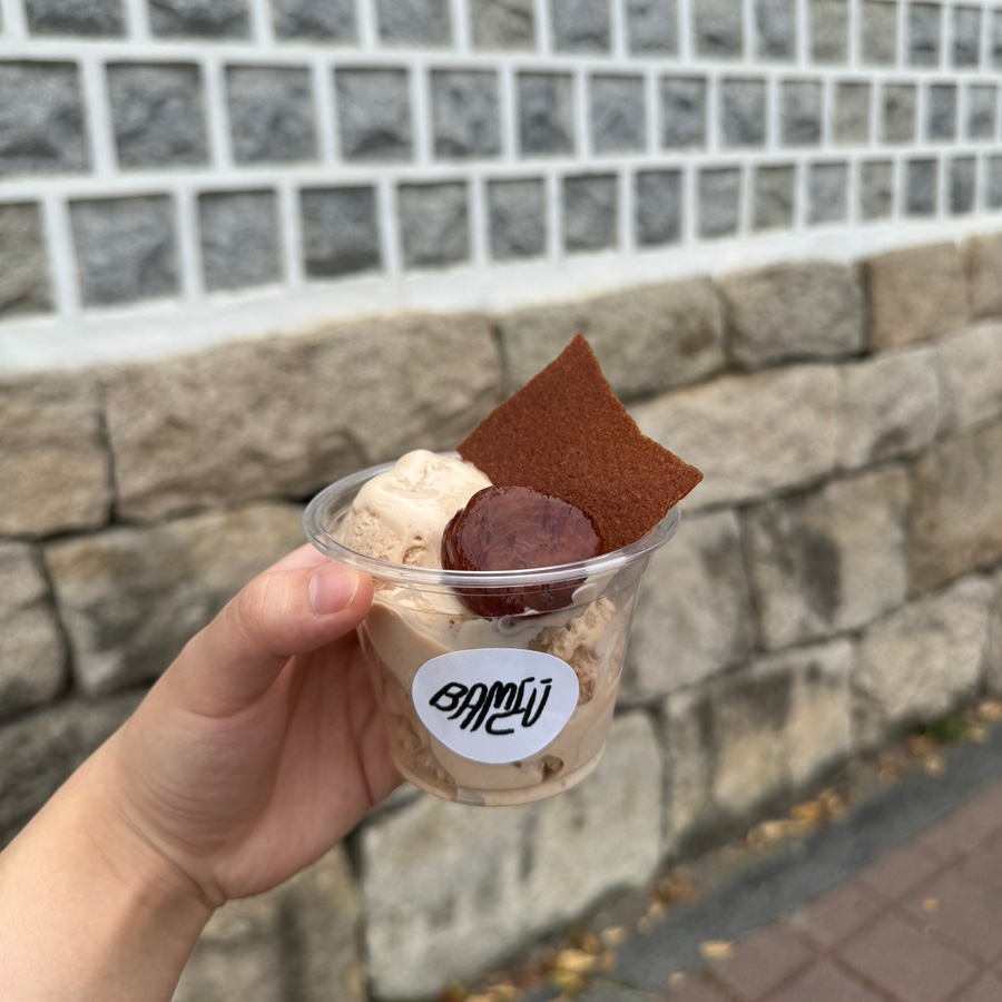 pooh_zip이 찍은 사진입니다. 2층 한옥 외관 아래 BAMEU 간판과, 밤 아이스크림 컵을 손에 들고 돌담을 배경으로 찍은 사진입니다.