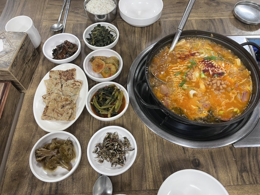 oyj0132가 찍은 사진입니다. 한옥식 나무 칸막이로 나뉜 테이블과, 보글보글 끓는 부대찌개에 밑반찬 여러 접시가 둘러진 상차림이 담겼습니다.