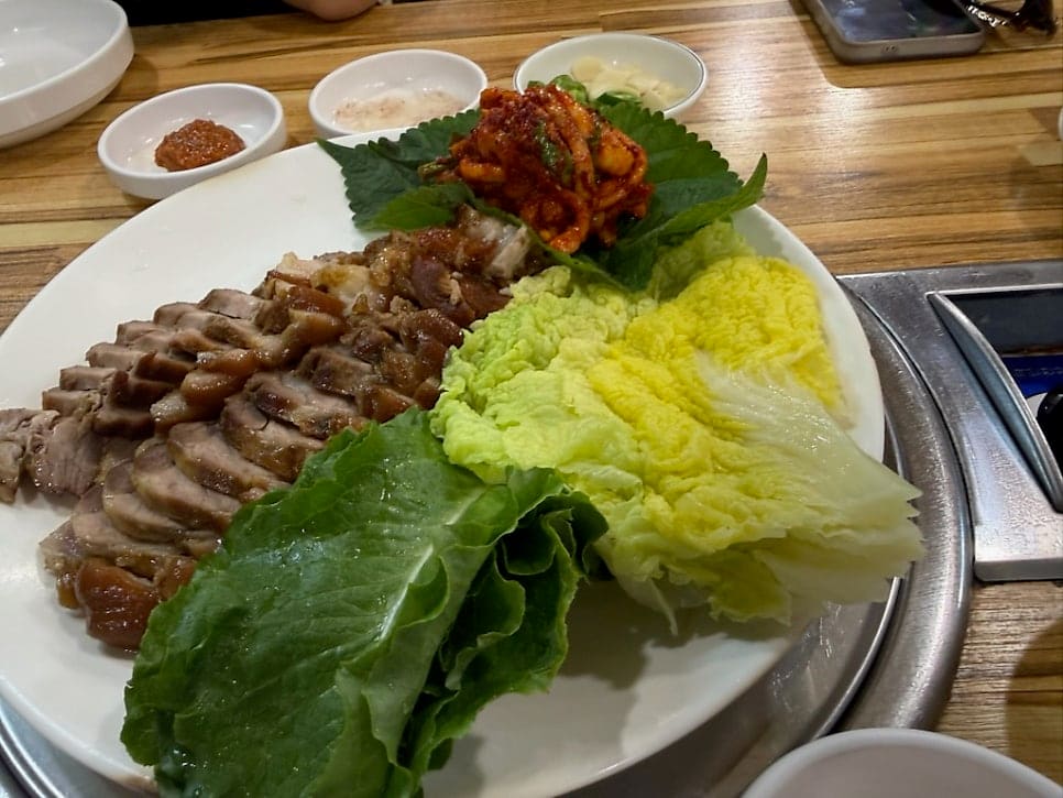 woooooon0716이 찍은 실내입니다. 굵은 나무 대들보가 그대로 드러난 천장 아래로 상 테이블이 줄지어 있고, 창문에는 상호가 새겨져 있습니다.