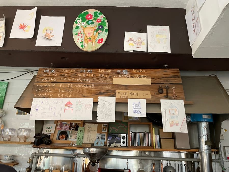 uuzaen이 촬영한 한옥 카페입니다. 처마 밑 낡은 램프가 달린 외관과, 로스팅 기계 옆으로 마른 꽃가지가 매달린 카운터 안쪽 풍경입니다.