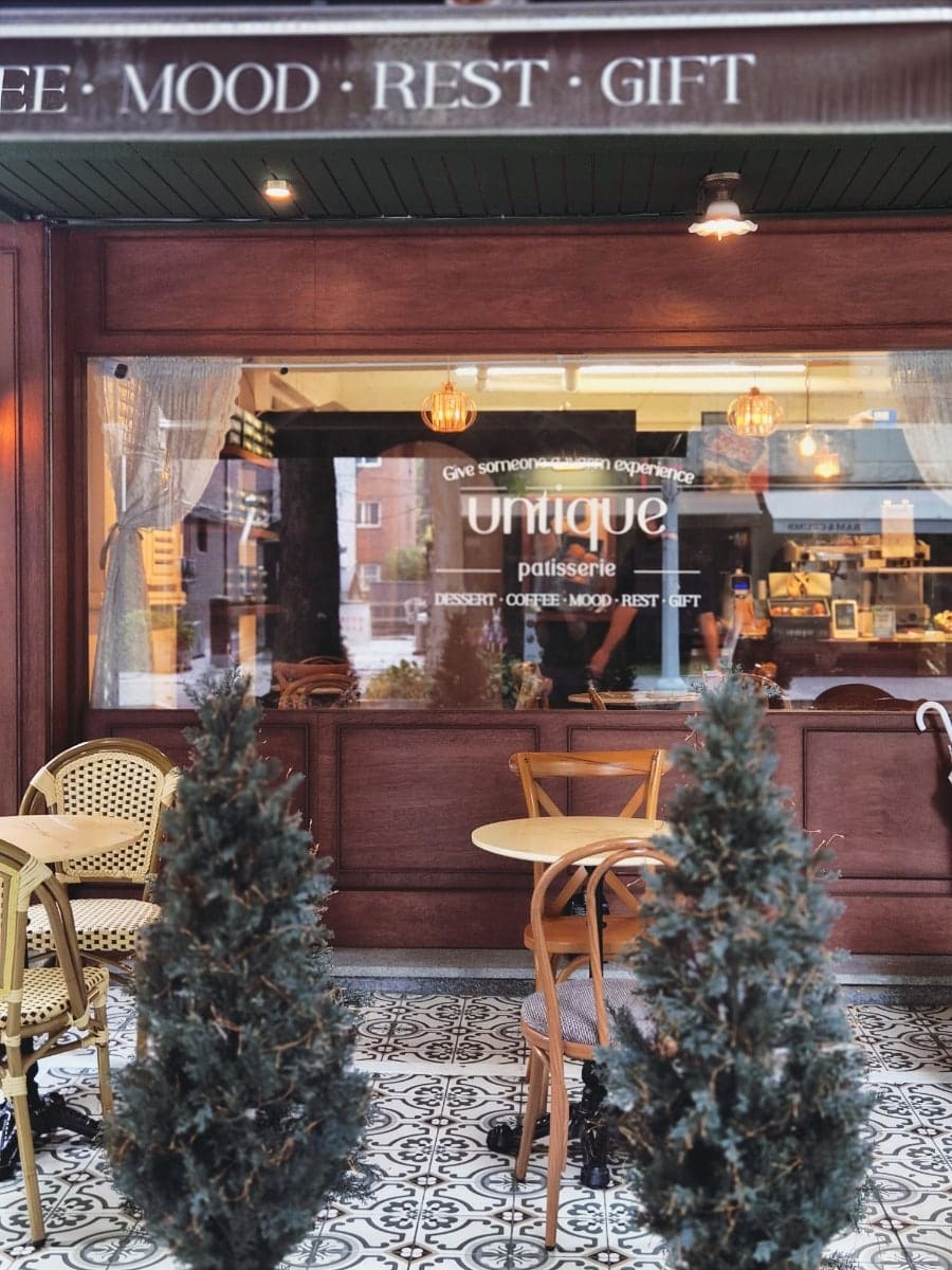 카페의 외관과 입구 풍경입니다. 딥그린 컬러의 건물 외관과 따뜻한 우드톤의 인테리어가 마치 유럽의 작은 마을 베이커리에 온 듯한 감정을 불러일으킵니다.