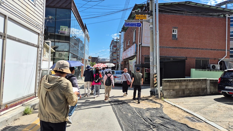 lila5151이 담은 금리단길 좁은 골목입니다. 붉은 벽돌 건물 사이로 난 길을 따라 사람들이 줄지어 걸어 들어가는 장면인데,