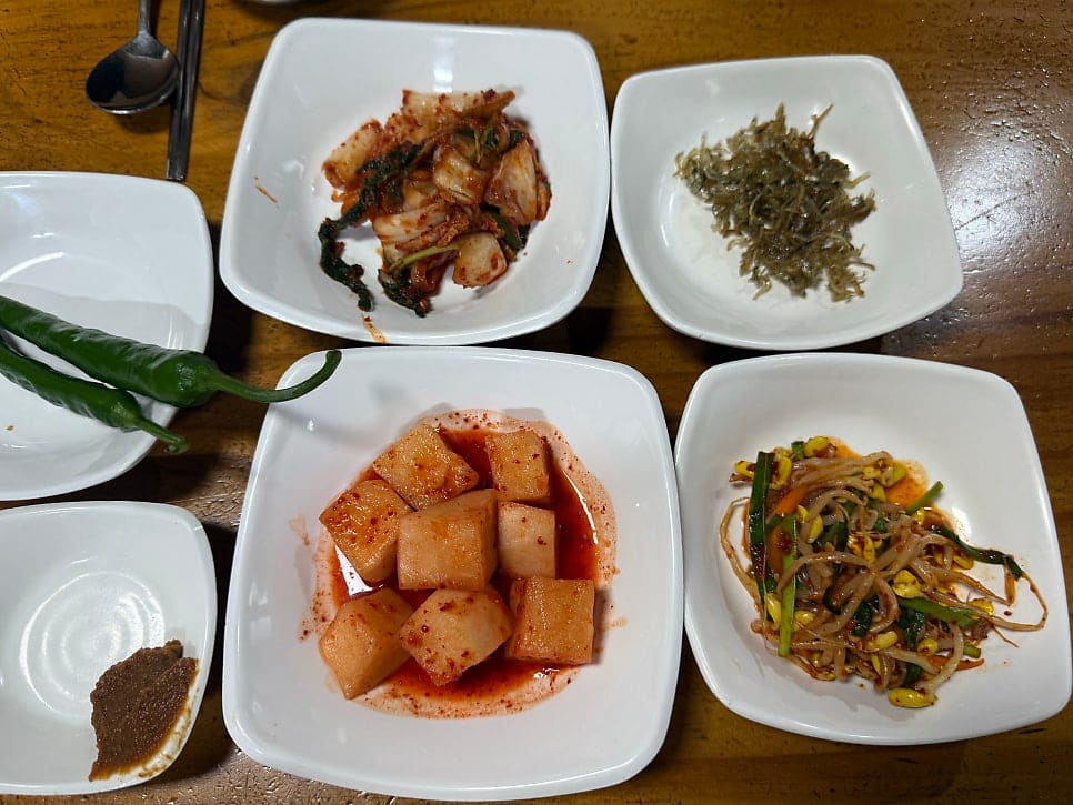 dongchang1117이 남긴 밑반찬과 한우무우국입니다. 깍두기, 겉절이, 콩나물무침이 한 상 가득하고, 맑은 국물 사이로 무와 소고기,