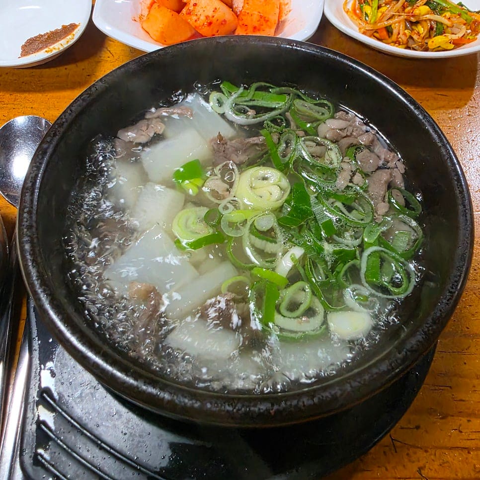 dongchang1117이 남긴 밑반찬과 한우무우국입니다. 깍두기, 겉절이, 콩나물무침이 한 상 가득하고, 맑은 국물 사이로 무와 소고기,