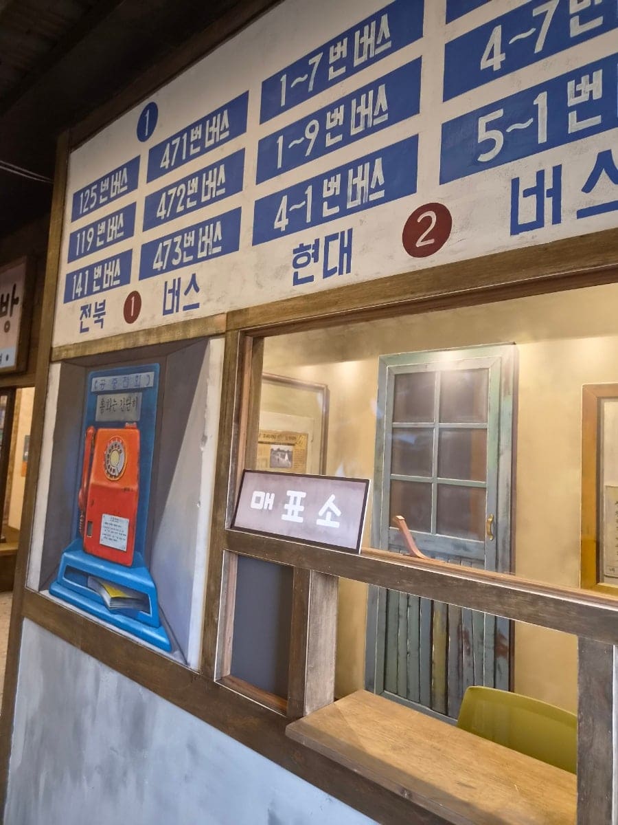 roundcake_이 찍은 추억전시관 입구와 내부입니다. 건물 벽면 가득 〈8월의 크리스마스〉 장면이 그려져 있고, 안쪽에는 옛날 버스 노선표와 매표소가 재현되어 있습니다.
