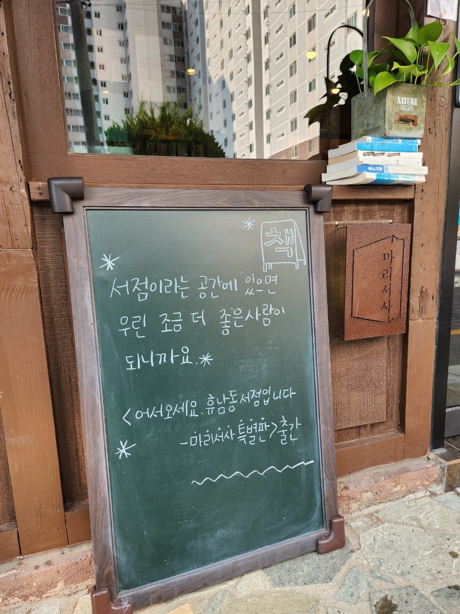 sspeechlesss가 찍은 가게 외관과 입구 칠판입니다. 파란 양철지붕을 인 낡은 목조 건물에, 나무 문패와 칠판 입간판이 나란히 놓여 있습니다.