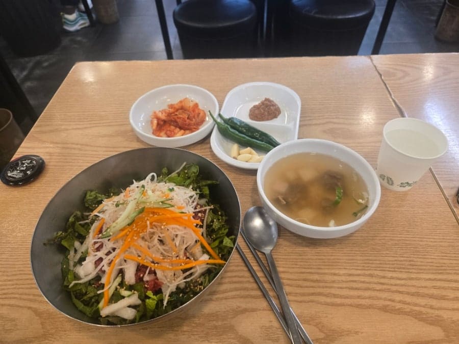육회비빔밥과 함께 나온 기본 상차림입니다. 김치, 양념장, 청양고추, 마늘, 그리고 따뜻한 소고기 무국이 함께 놓여 있습니다.