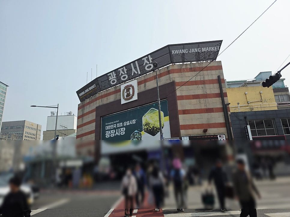 광장시장 정문 간판 아래로 사람들이 드나들고, 시장 안쪽 HBAF 아몬드 매장 앞에도 발길이 이어집니다. 이른 시간에도 걸음은 끊이지 않습니다.