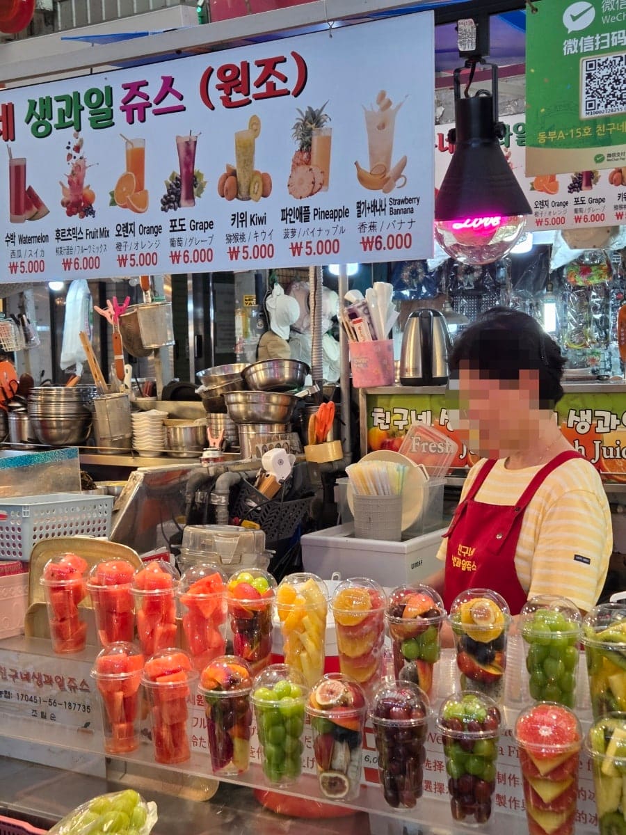 육회골목 벤치에 자리를 잡고 앉은 손님과, 생과일주스를 파는 상인. 카메라를 든 사람과 그저 저녁을 먹으러 온 사람이 같은 지붕 아래 나란히 있습니다. 누구는 사진을 찍고,