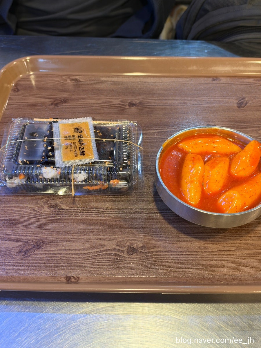 빨간 패널로 마감된 자리에 스테인리스 상판 테이블과 나무 의자가 놓여 있습니다.