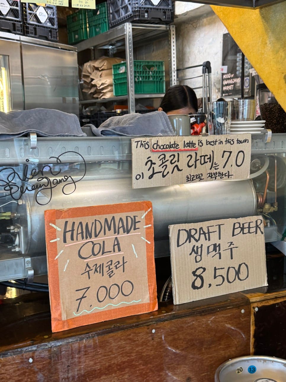 어니언의 오픈형 공간과 카운터. 메뉴판에 적힌 'Midnight Onion', 'Espresso Martini'와 바리스타의 손. 시장의 러프함과 힙한 감성이 만나는 현장입니다.
