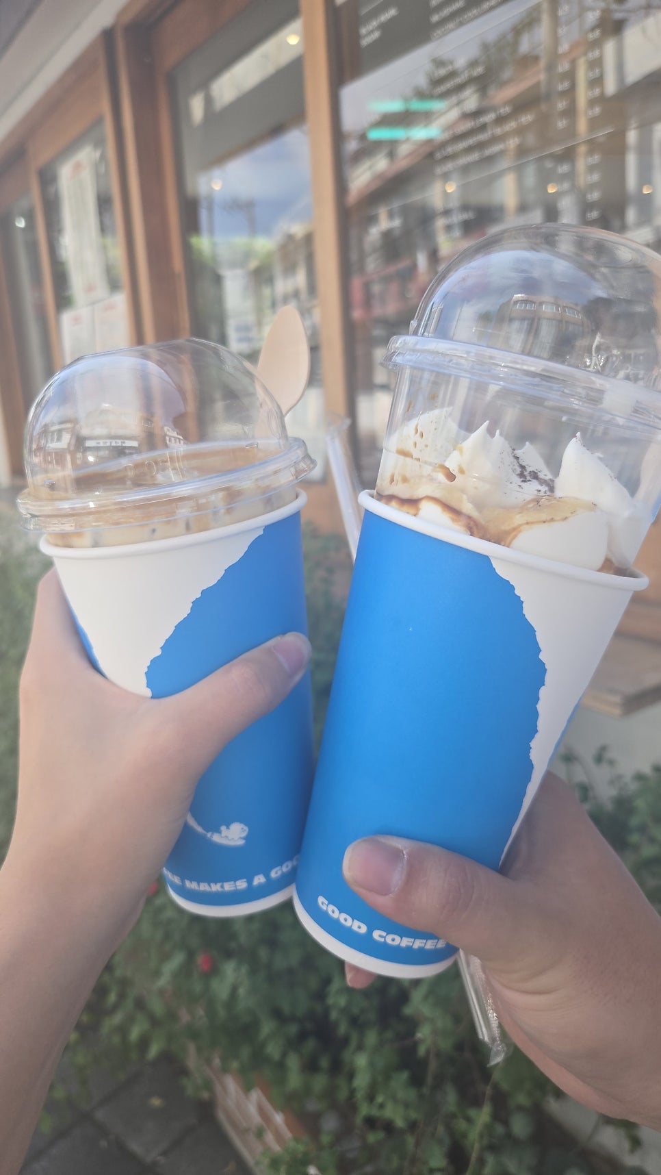 dongking6과 jandikch가 각각 받아 든 커피를 찍었습니다. GOOD COFFEE 문구가 적힌 컵 두 잔을 매장 창문 앞에서 부딪히는 모습과,