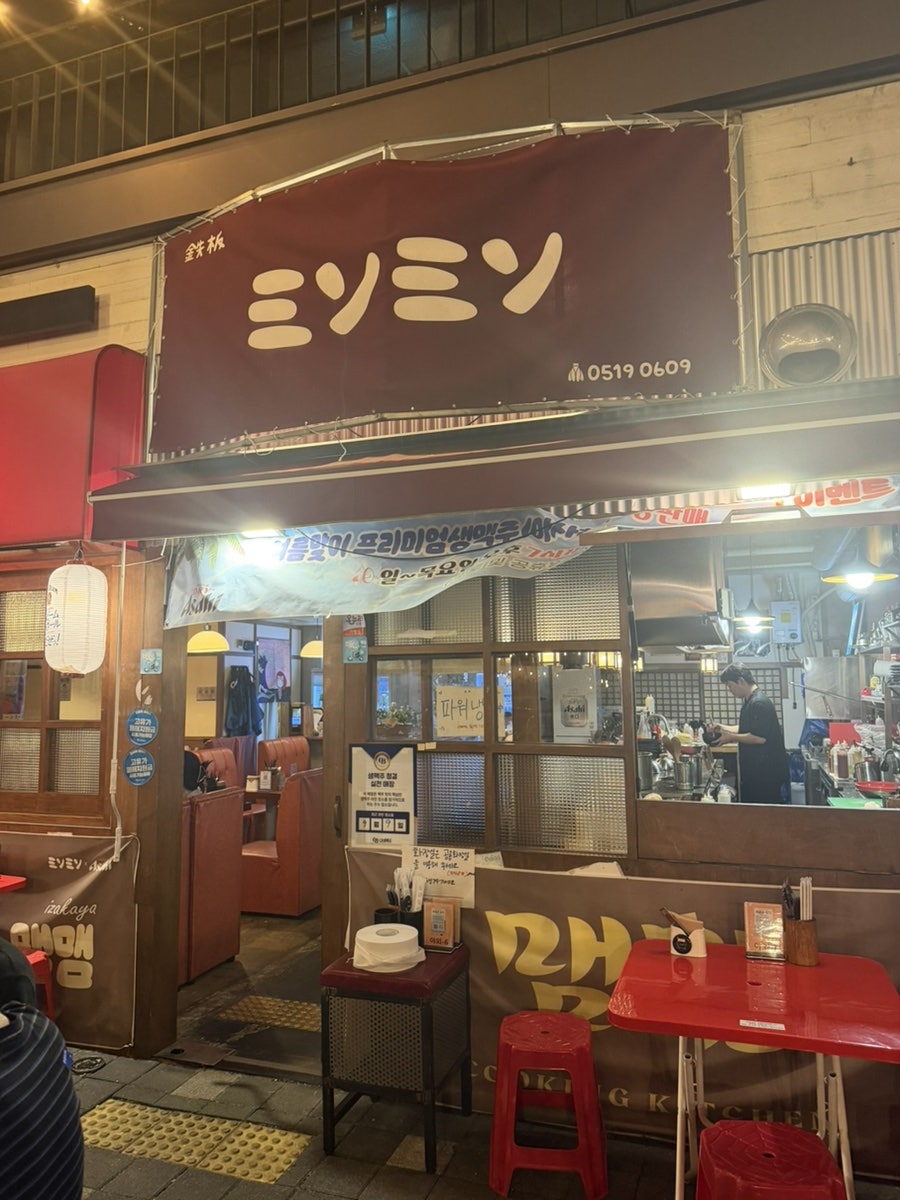 1_kyul이 야외석과 입구를 각각 찍었습니다. 줄전구 아래 빨간 플라스틱 테이블과 의자가 한옥 지붕을 배경으로 늘어서 있고,