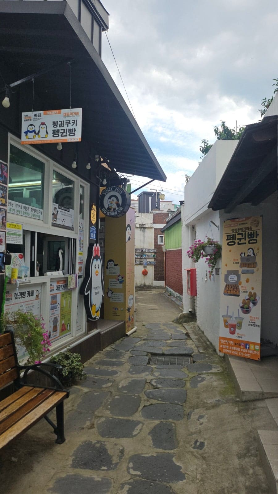 kpj1750이 펭귄마을을 지나며 찍은 두 장면입니다. 펭귄빵을 파는 카페 간판과, 옛 사진들을 모아 벽에 붙인 작은 전시 공간이 몇 걸음 차이로 나란히 있었다고 적었습니다.