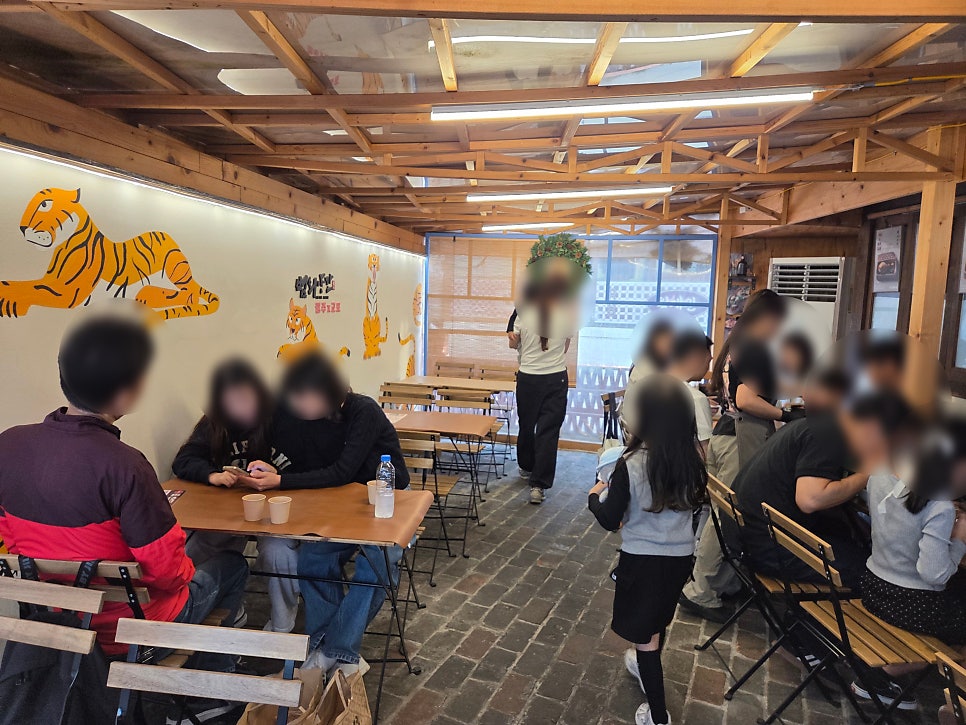 vldhsk213이 담은 저녁 시간의 북적이는 실내입니다. 벽화 속 호랑이 두 마리가 가득 들어찬 테이블을 내려다보는 모습이 이 골목의 저녁 풍경을 보여줍니다.