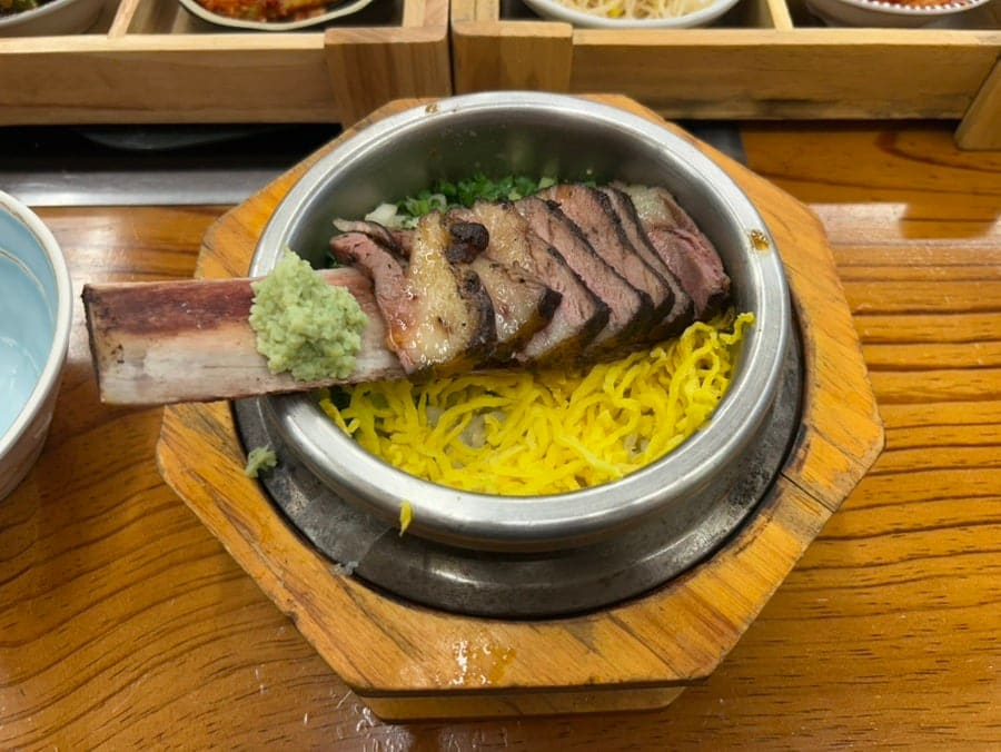 6yeargap이 남긴 우대갈비솥밥과 밑반찬입니다. 뼈째 올라온 갈비와 노릇한 누룽지, 여덟 칸짜리 반찬함이 한 상에 함께 놓여 있습니다.