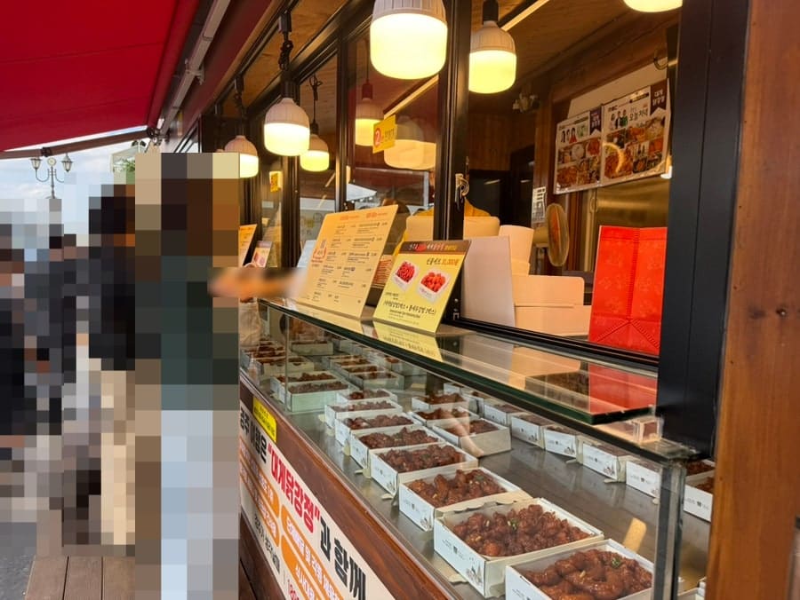 madtraveler가 담은 경주대게닭강정 유리 진열장입니다. 따뜻한 조명 아래 포장까지 끝난 상자들이 가지런히 줄지어 있는 모습을 보여줍니다.