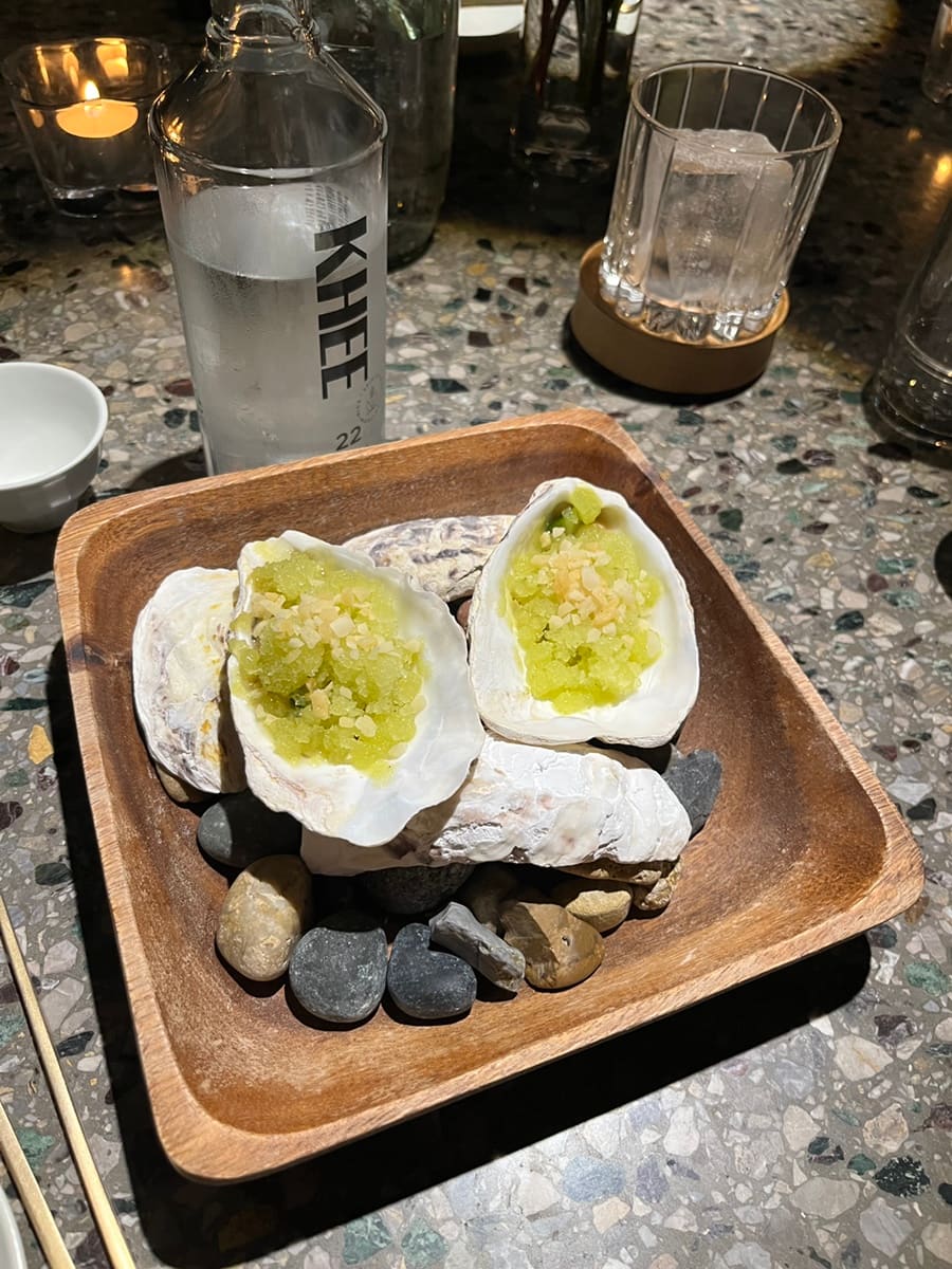 sobbo9705님이 남긴 사진입니다. 전복 껍데기와 자갈을 그릇 삼아 낸 안주 두 접시, 그 옆에 놓인 KHEE 소주병까지 담았습니다. 재료 본연의 맛을 살렸다는 기록처럼,