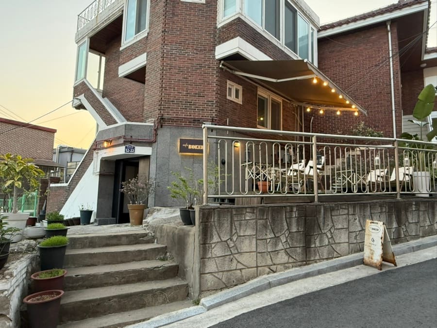 futabatown이 촬영한 회나무로의 어느 카페 테라스입니다. 저녁에도 조명이 켜진 빈 테이블과 붉은 벽돌 건물의 외관이 손님을 기다리는 지금의 풍경을 보여줍니다.