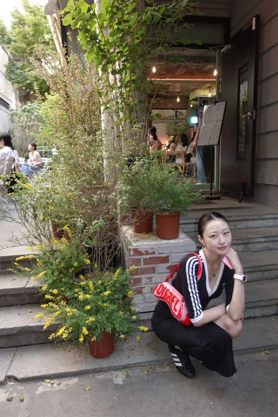 hanseon216이 촬영한 회나무로의 낮 풍경입니다. 화분과 덩굴이 감싼 계단 입구에 사람이 잠시 머무는 모습이 이 골목의 초록을 보여줍니다.