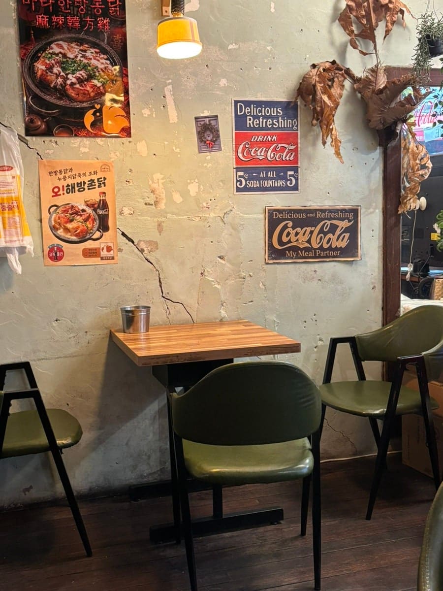 초록 의자가 놓인 아늑한 구석 자리와, 오래된 콜라 광고판 옆에 걸린 '오!해방촌닭' 홍보 포스터입니다. 주말 오후인데도 웨이팅 없이 들어갔고,