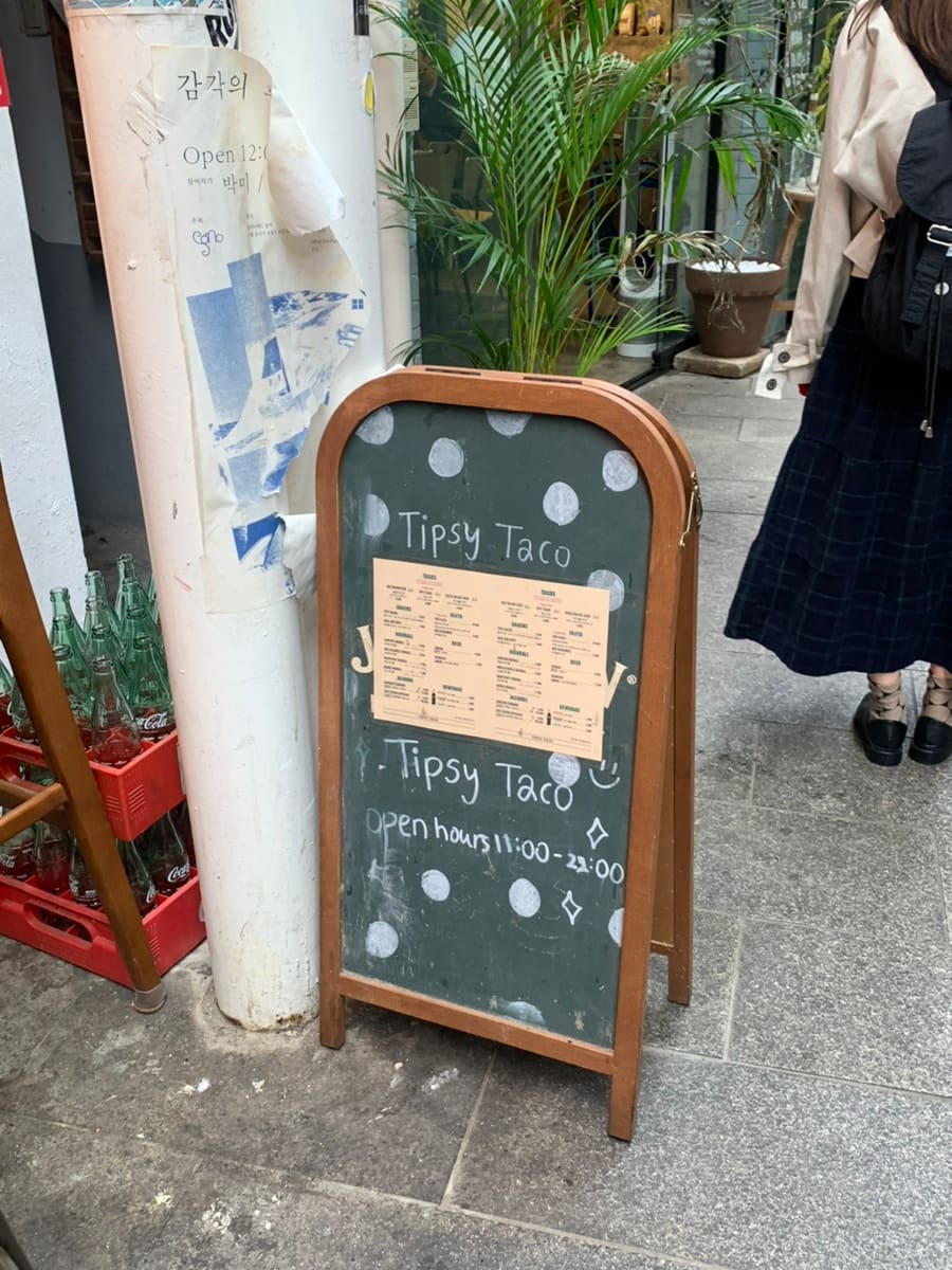 화분과 유리병이 놓인 입구의 입간판과, 위스키와 잔이 걸린 바 카운터입니다. 시그니처 팁시 타코의 된장과 과카몰리 조합을 추천한다고,