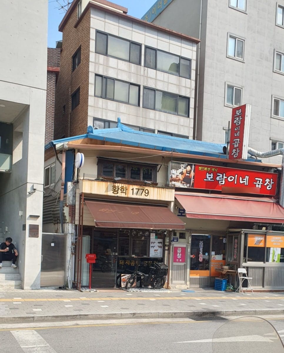 jsyou2994가 촬영한 황학 1779 건물과 그 옆 전자골목입니다. 파란 양철지붕을 인 낮은 건물 하나가 새 건물들 사이에 끼어 있고,