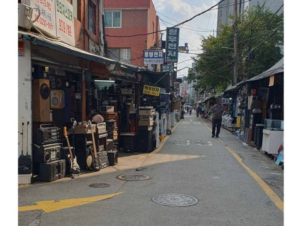 jsyou2994가 촬영한 황학 1779 건물과 그 옆 전자골목입니다. 파란 양철지붕을 인 낮은 건물 하나가 새 건물들 사이에 끼어 있고,