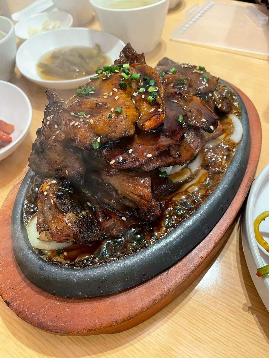 zebra_context는 주방 창 너머로 직원이 숯불 위에서 갈비를 붓으로 발라 가며 굽는 장면을 포착했습니다.