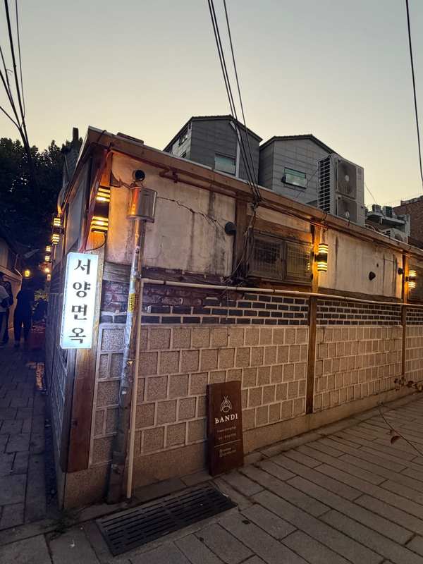 kang_stesti는 웨이팅 방법까지 꼼꼼히 기록했습니다. 어둑해질 무렵 불을 밝힌 세로 간판과, 패브릭 아트가 걸린 창 너머 저녁의 안뜰을 남겼습니다.