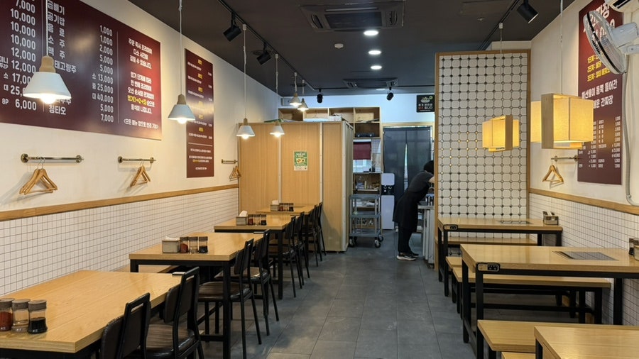 bak_js가 찍은 사진입니다. 빨간 문과 간판이 선명한 입구를 먼저 담았고, 이어 매장 안쪽까지 비추는 조명과 나란히 놓인 테이블을 보여줍니다.