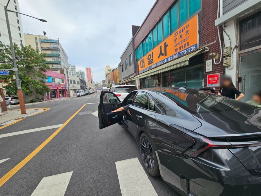 노란 외벽에 since 1953이 적힌 한미서점과 그 앞을 지나는 차들. 오래된 상가 건물들이 나란히 이어진 지금의 골목 풍경이다.