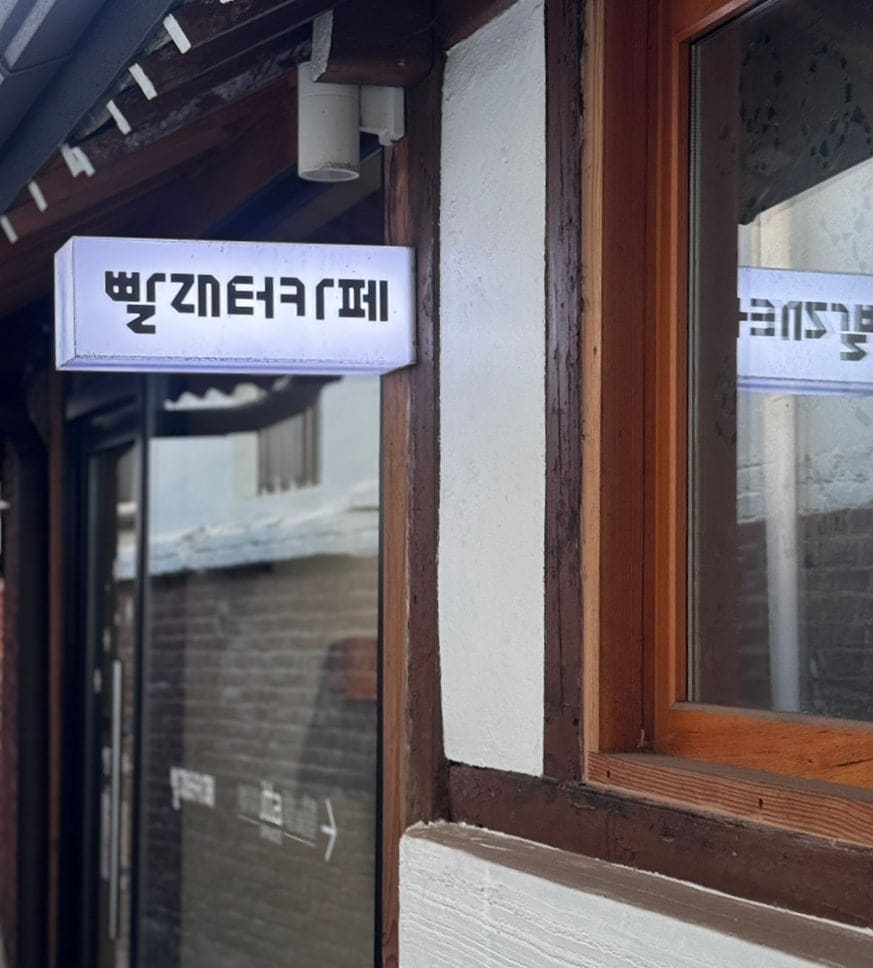 여인숙이 모여 있던 골목 어귀에 걸린 복합문화공간 배다리 아트스테이 1930 간판과, 그 안 빨래터카페의 불 켜진 사인.