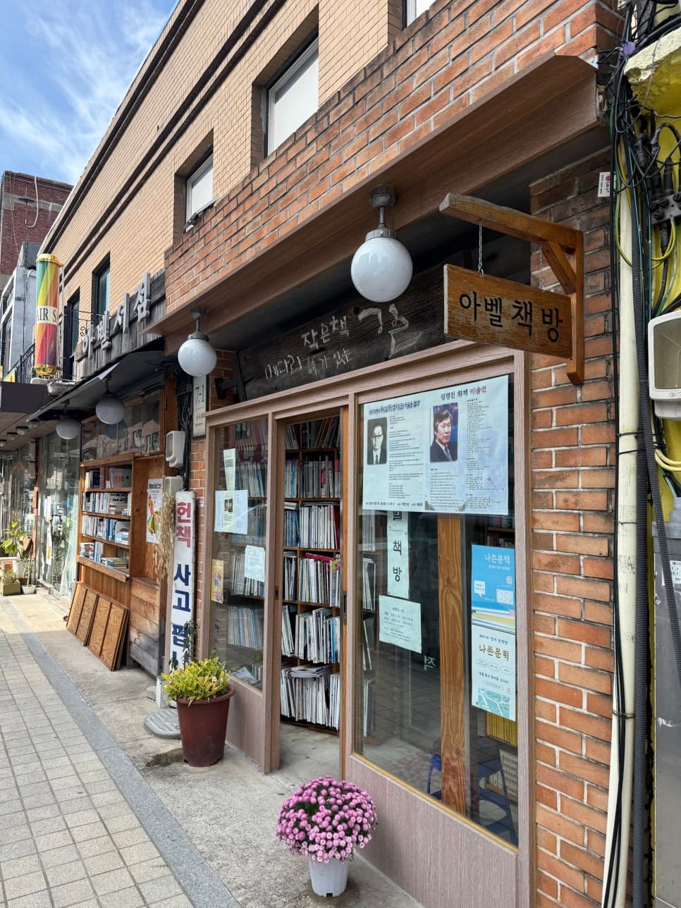 아벨책방 입구에 걸린 작은책 詩가 있는 마을이라 새긴 나무 간판과, 그 아래 빼곡히 쌓인 책들.