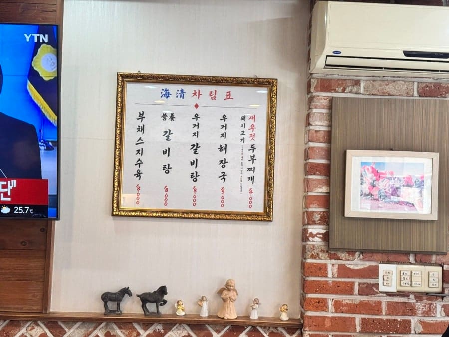 milkyrise가 남긴 사진입니다. 벽에 걸린 오래된 차림표 액자와 작은 소품들이 놓인 내부, 그리고 당면과 고기를 건져 올리는 뚝배기 속 장면을 담았습니다.