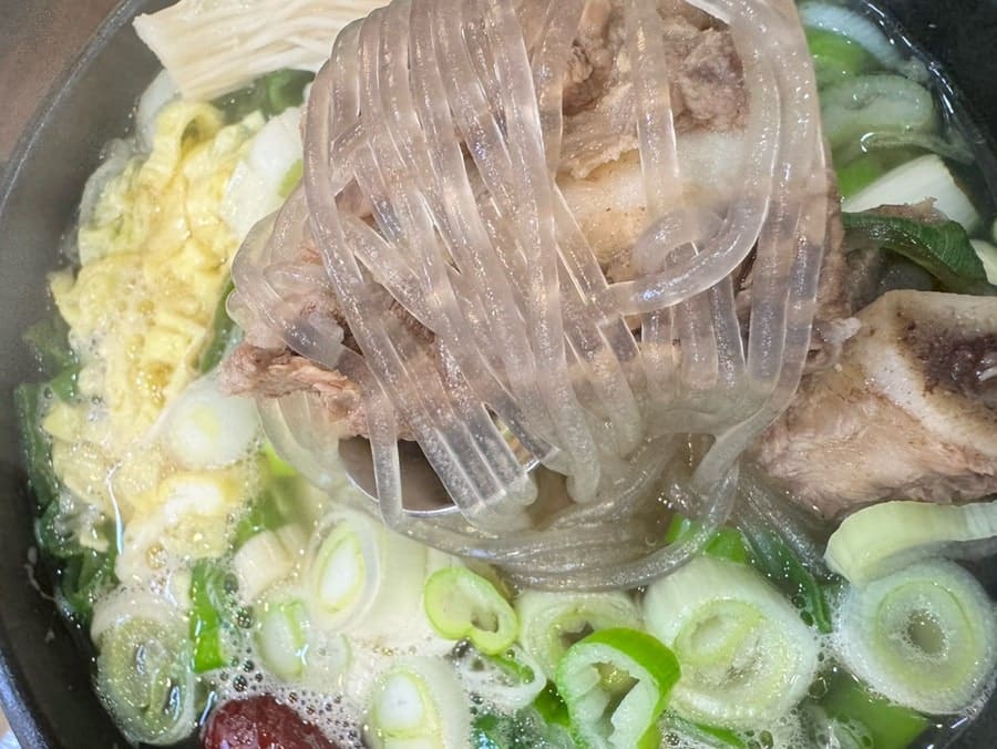 milkyrise가 남긴 사진입니다. 벽에 걸린 오래된 차림표 액자와 작은 소품들이 놓인 내부, 그리고 당면과 고기를 건져 올리는 뚝배기 속 장면을 담았습니다.