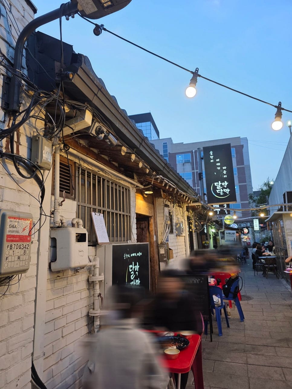 ddngbbng는 전시를 보고 나와 야장이 당겼다가 이 골목까지 흘러왔다고 적었습니다. 저녁 하늘 아래 검은 간판에 달막달막이라는 글자가 서 있고,