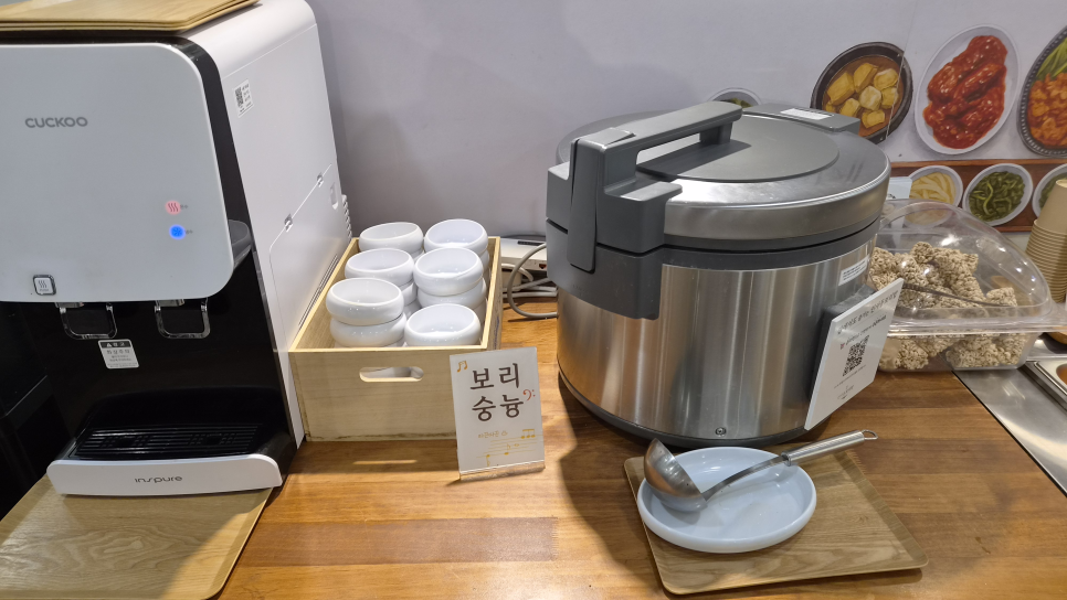 hs010195는 '쌀밥'과 '보리밥' 팻말이 붙은 밥솥 두 개와, 그 옆 보리숭늉 코너를 함께 찍었습니다.