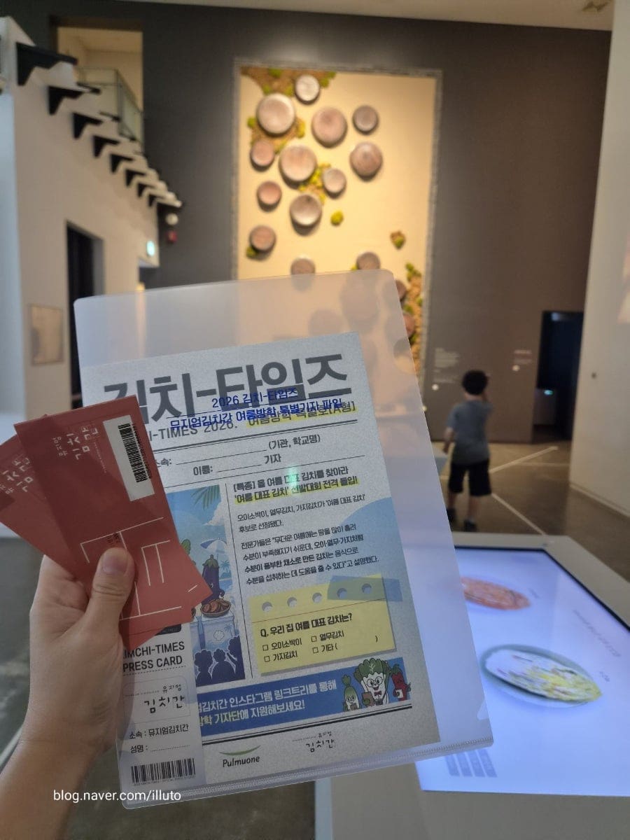 illuto는 전시장 한쪽에 걸려 있던 작년 공모전 수상작들을 보며 아이가 큰 관심을 보였다고 적었습니다. 한 장은 어린이들이 그린 음식 그림이 검은 벽에 줄지어 걸린 모습이고,