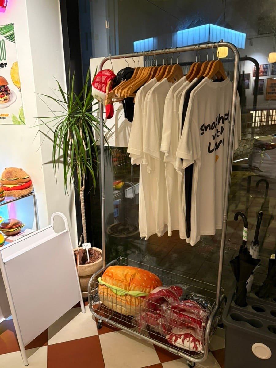 zzlovely92가 담은 사진 벽과 밤의 굿즈 코너입니다. 'THE BEST IN TOWN' 포스터 곁으로 직원과 손님, 노을 풍경을 담은 액자가 어지럽게 걸려 있고,