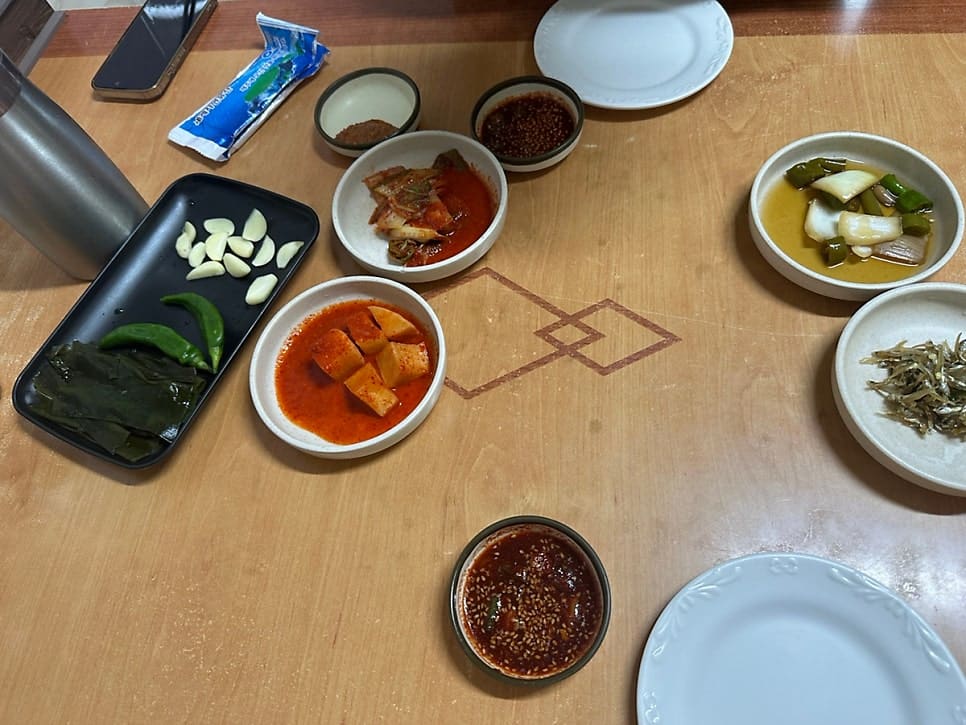 dlsqja0622가 담은 저녁 시간의 매장 안과 밑반찬입니다. 좁은 통로 양옆 테이블마다 손님이 앉아 있고 직원이 그 사이를 오가는데,