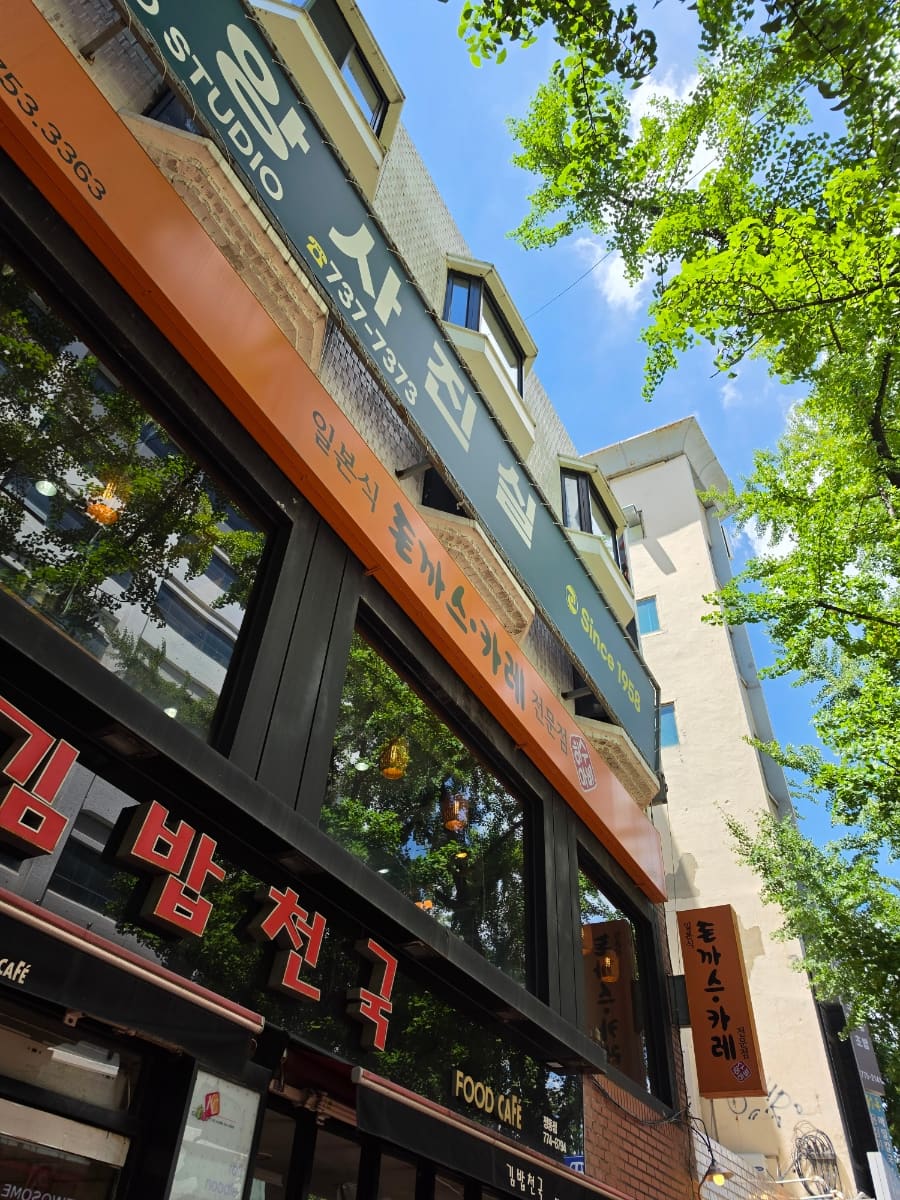 허수아비의 외부 간판입니다. 주황색과 회색 간판에 '허수아비', '돈까스', 일본식 글자와 영문 'FOOD CAFE'가 표기되어 있으며,