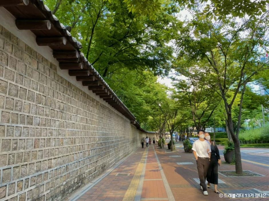 왼쪽은 덕수궁 돌담을 따라 이어지는 정동길 보행로를 넓게 담은 장면으로, 가로수 그늘 아래 벤치에 앉은 사람과 산책하는 시민들이 보인다.